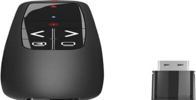 A sleek presentation clicker beside a laptop on a wooden desk.